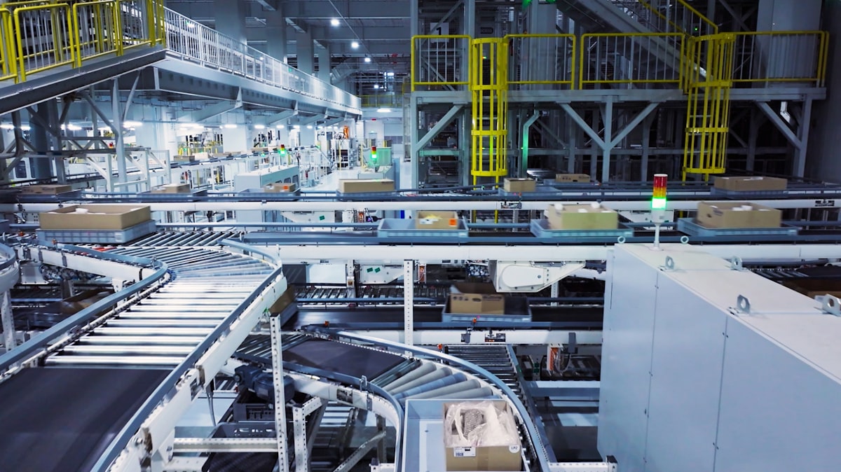 Industrial roller and belt conveyor system moving materials through a production facility